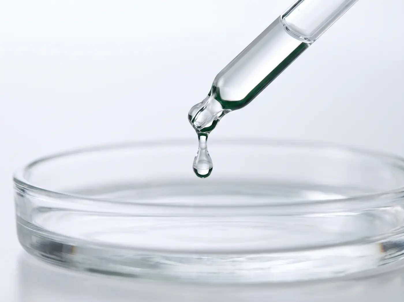 Laboratory dropper releasing a droplet into a glass dish